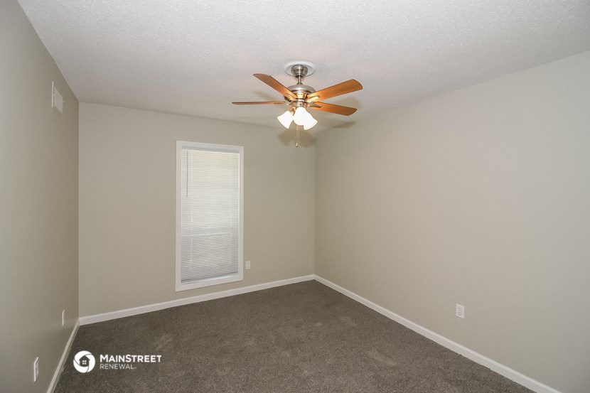 an empty room with a ceiling fan and a window