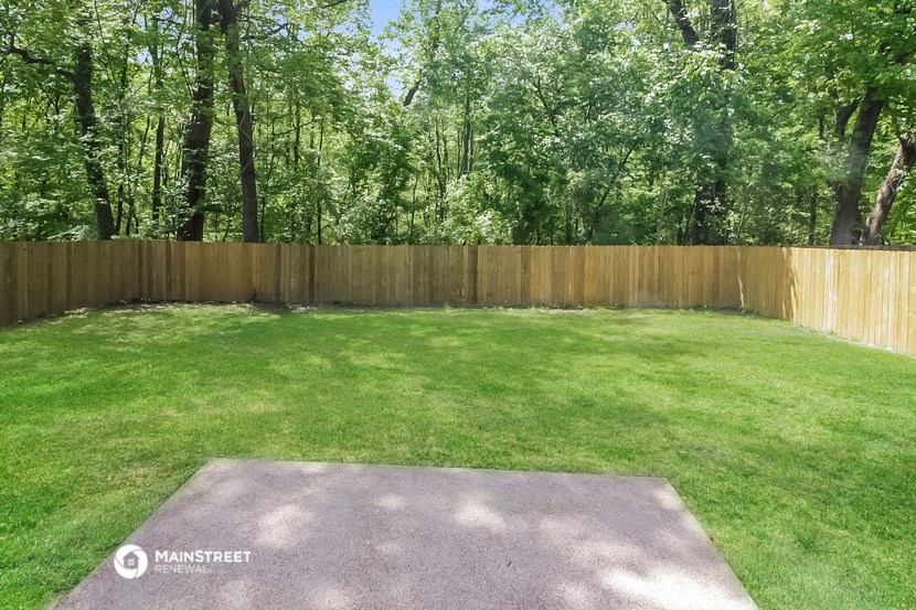 a backyard with a wooden fence and a grassy area with a lawn
