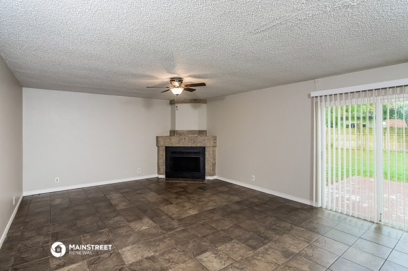 a living room with a fireplace and a ceiling fan