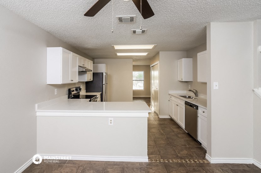 an empty kitchen with white cabinets and a counter top