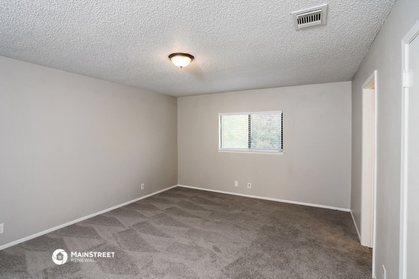 the spacious living room with carpet and a window
