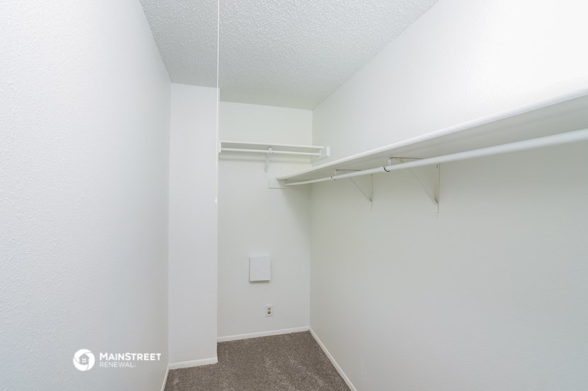 a spacious room with a closet and a white wall with a hanging rail and a