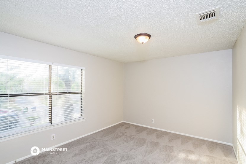 the spacious living room of an apartment with a large window