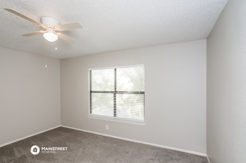 a living room with a large window and a ceiling fan
