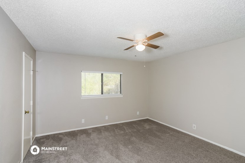 the spacious living room with ceiling fan and carpet