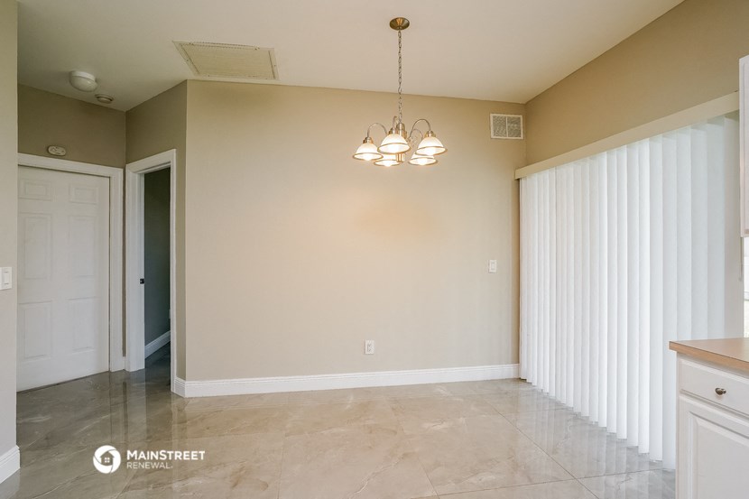 an empty dining room with white blinds and a chandelier