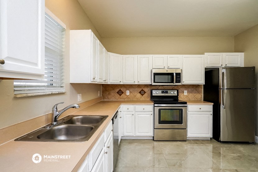 a kitchen with white cabinets and stainless steel appliances