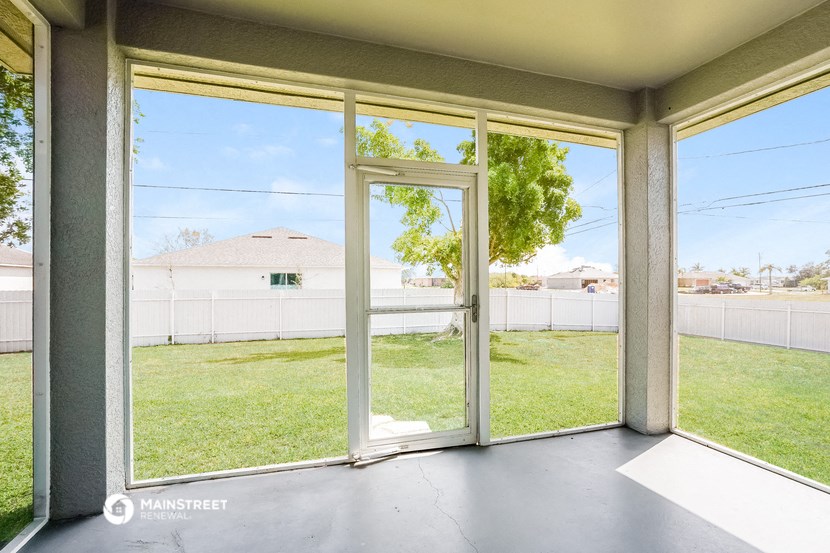a view of the yard from the inside of a room with glass doors