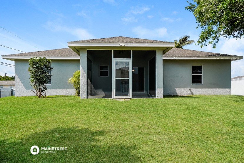 a small gray house with a lawn and a door