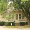A house with a porch and a tree in front.