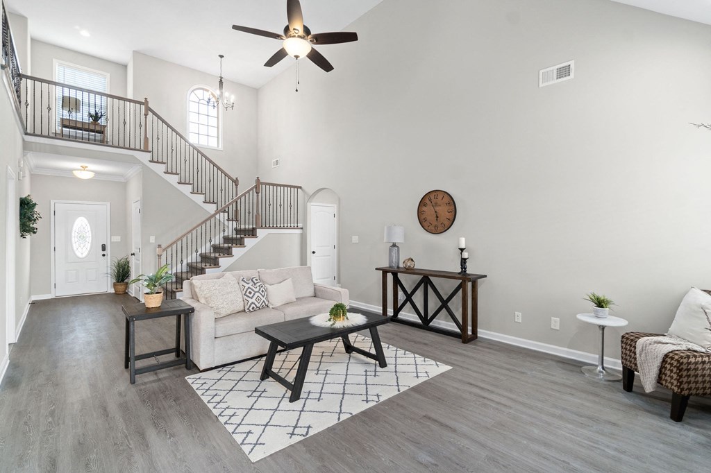 an open living room with a ceiling fan and a staircase