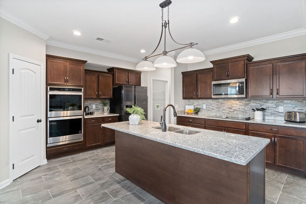 a large kitchen with wooden cabinets and a marble counter top