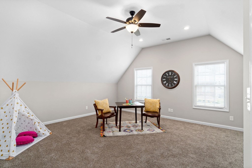 a living room with a ceiling fan and a table and chairs