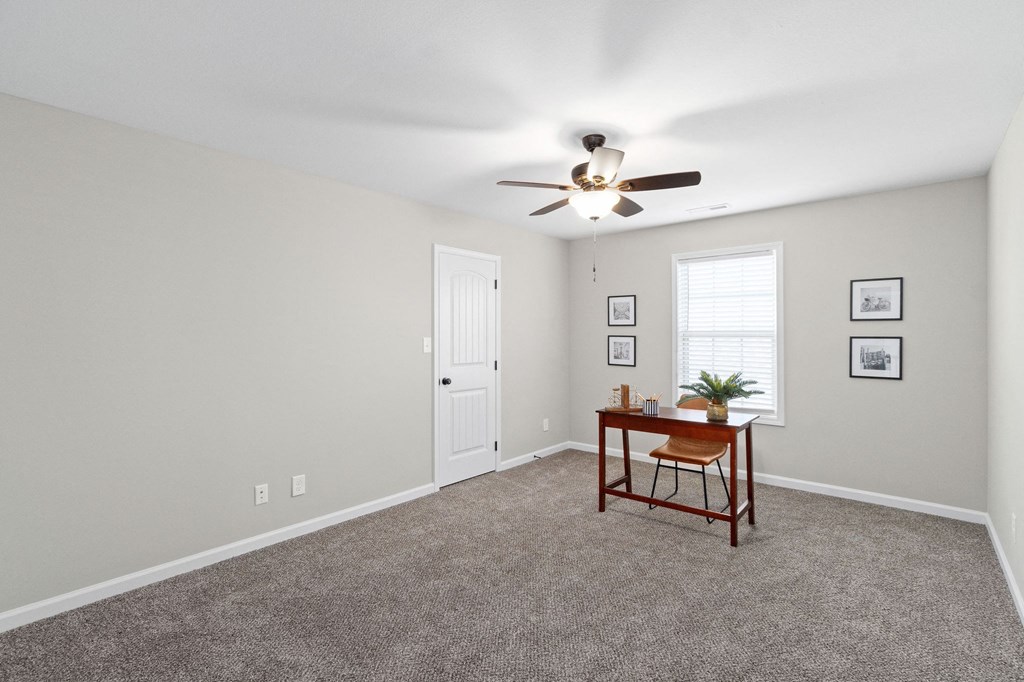an empty living room with carpet and a ceiling fan