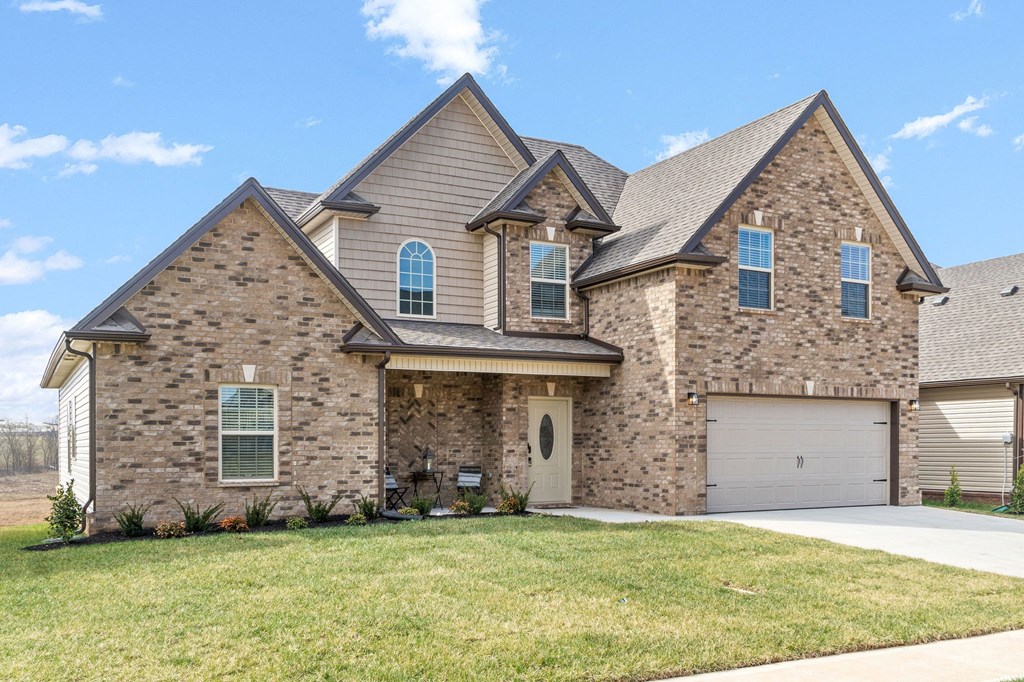 a large brick house with a garage and a lawn