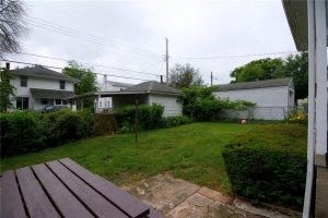 A backyard with a picnic table and a house in the background.