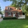 A red brick house with a white fence in front.