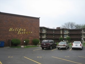 a parking lot with cars in front of a holiday terrace building
