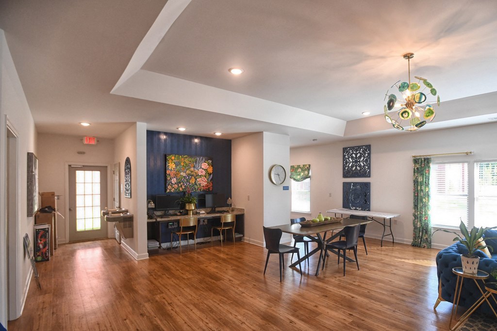 A dining room with a wooden floor and a large painting on the wall.