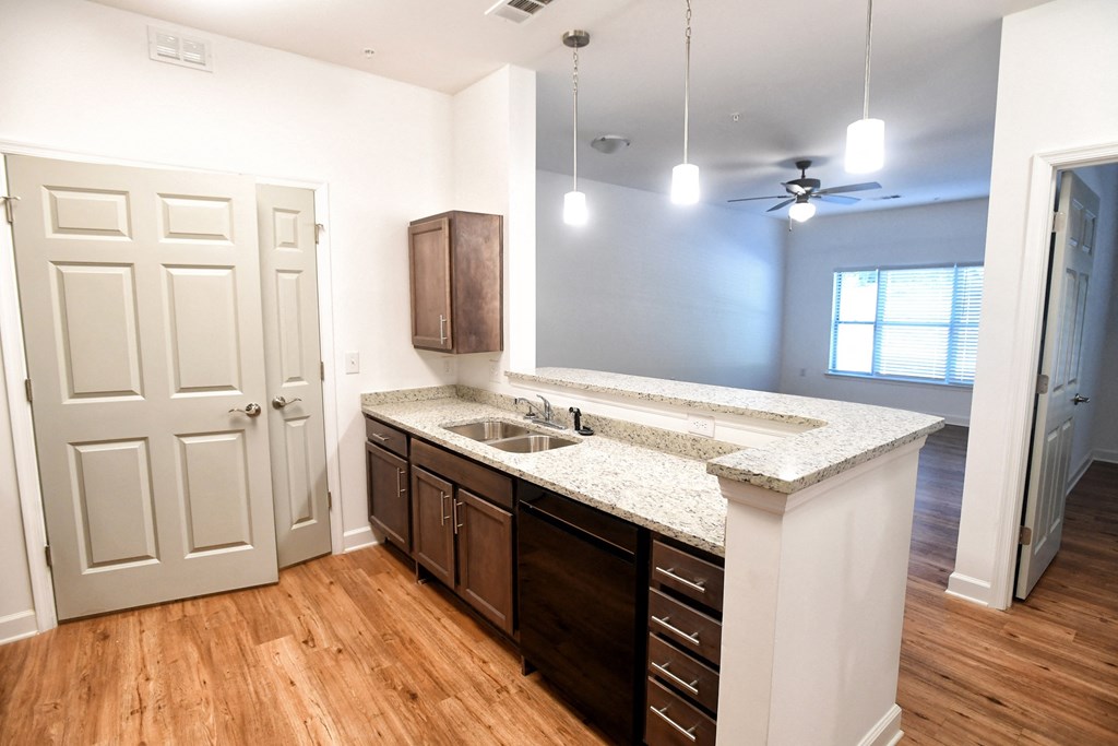 A kitchen with a white counter top and wooden floors.