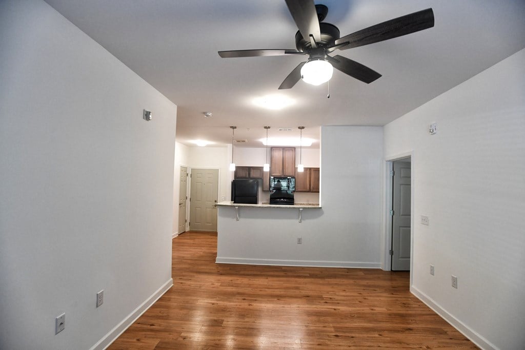 A room with a ceiling fan and wooden floors.