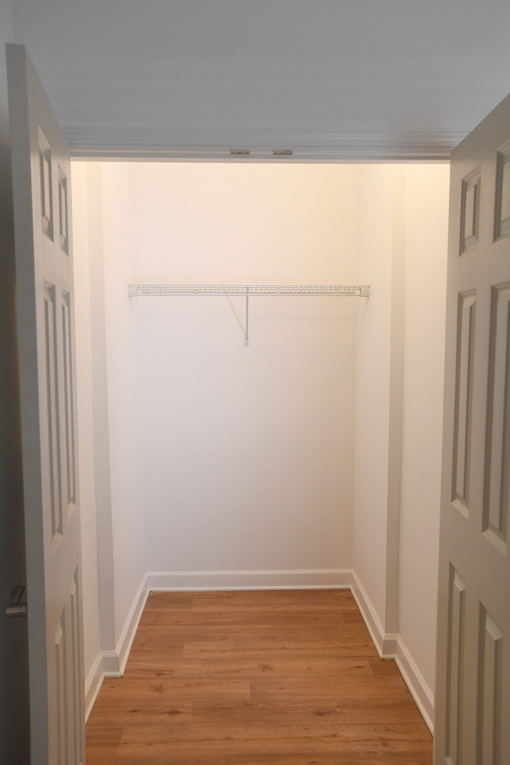 A white hallway with a wooden floor and a white wall.