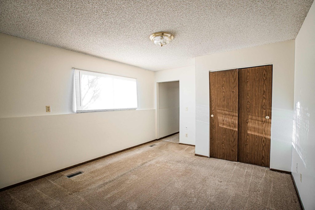 A room with a carpeted floor and a window.