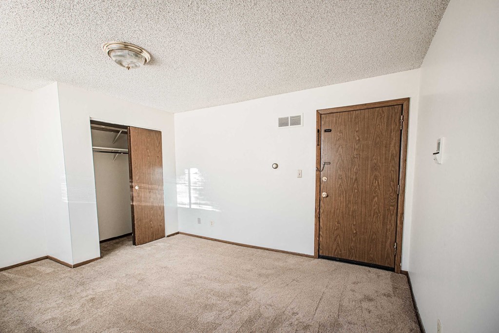 A room with a carpeted floor and two doors.