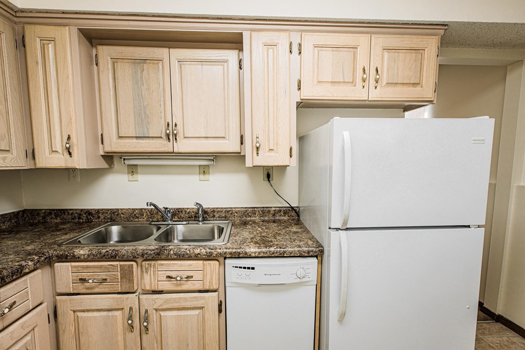 A white refrigerator is in a kitchen with wooden cabinets.