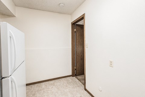 A white refrigerator sits in a kitchen next to a wooden door.