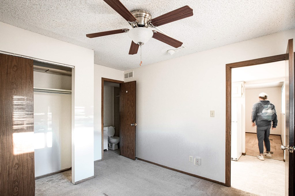 A man is standing in a room with a ceiling fan.