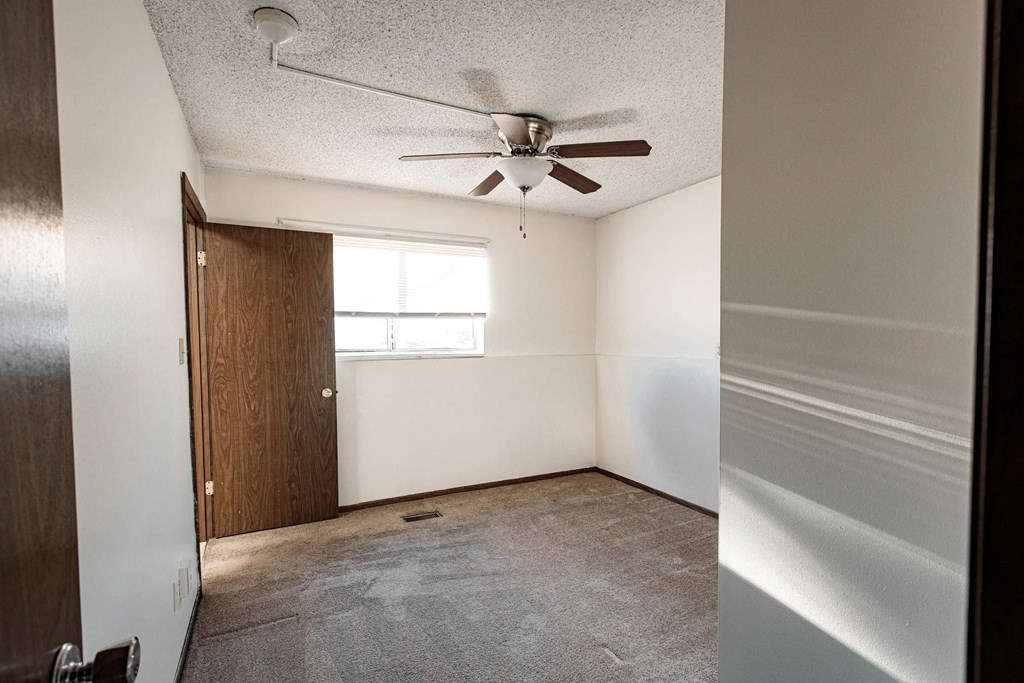 A room with a ceiling fan and a door.