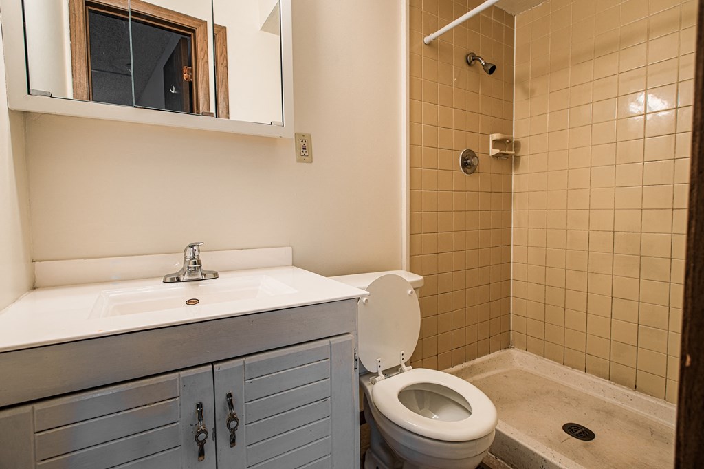 A bathroom with a toilet, sink, and mirror.