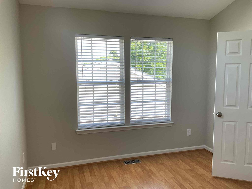 a living room with two windows and a wooden floor