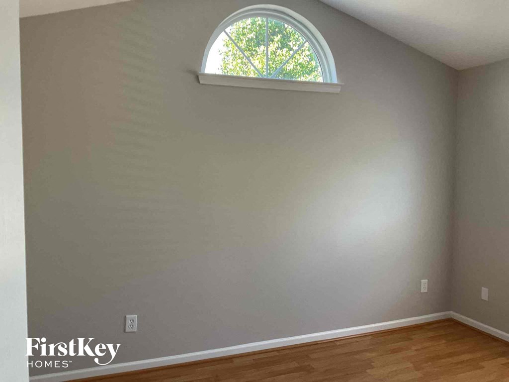 a bedroom with a window and a wooden floor