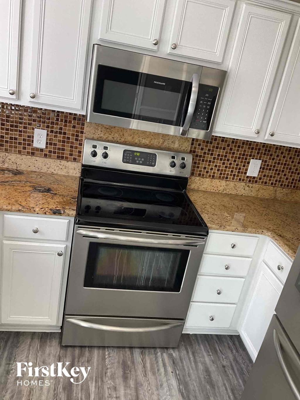 a kitchen with a stove and microwave and white cabinets