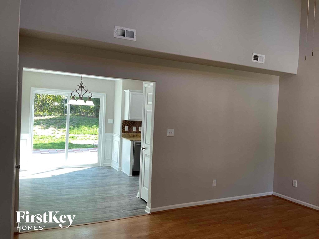 an empty living room with a door to the kitchen
