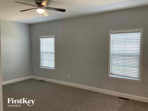 A room with a fan and two windows.