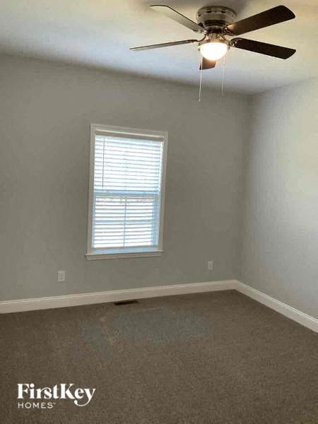 A room with a ceiling fan and a window with blinds.