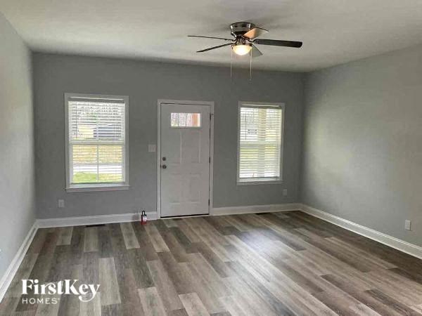 A room with a ceiling fan and wooden flooring.