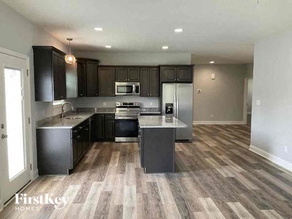 A kitchen with a refrigerator, microwave, oven, and sink.