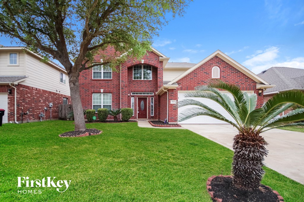 A red brick house with a palm tree in front.