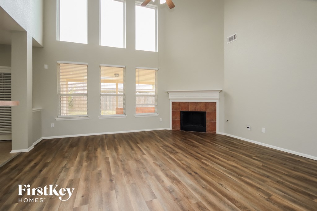 A spacious room with wooden floors and a fireplace.