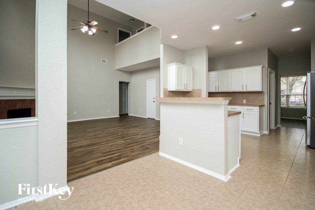 A kitchen with white cabinets and a wooden floor.