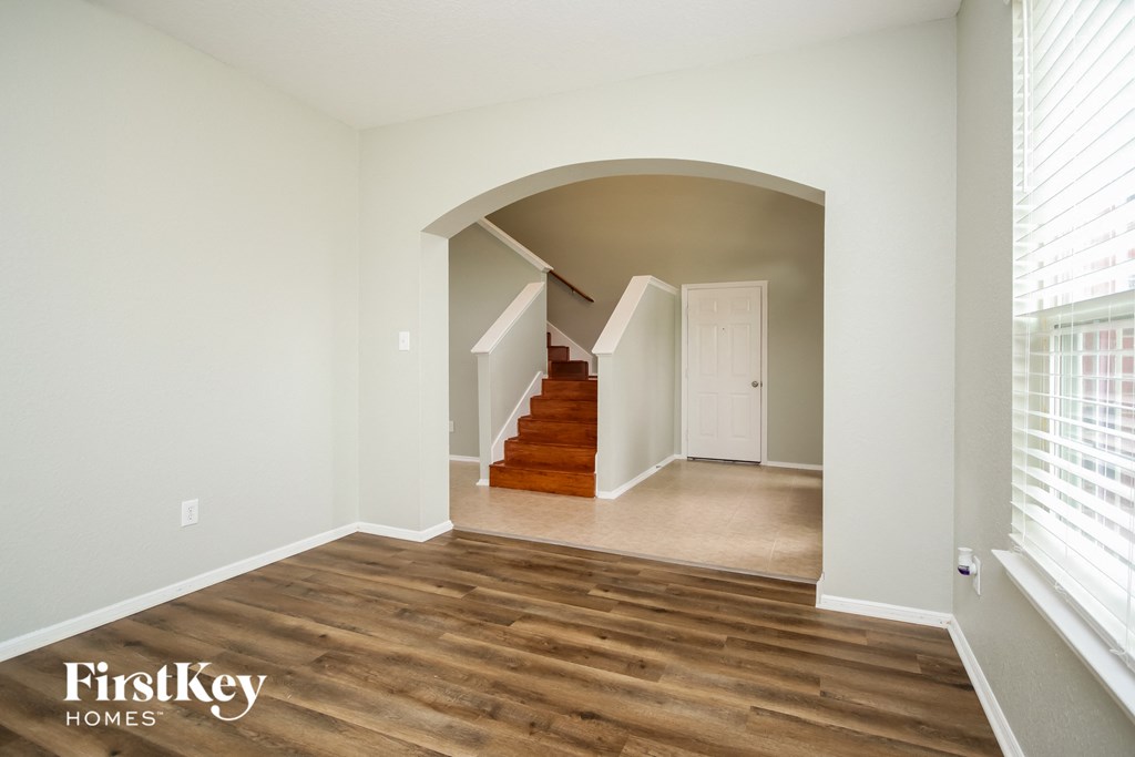 A room with wooden floors and a staircase leading to another room.