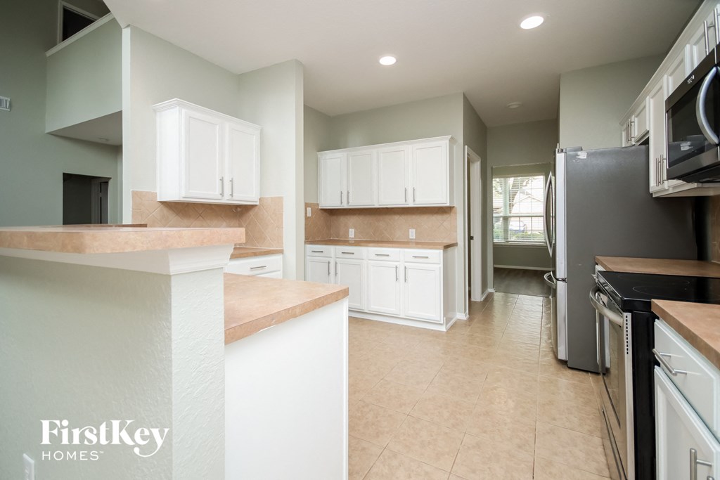 A kitchen with white cabinets and a black fridge.