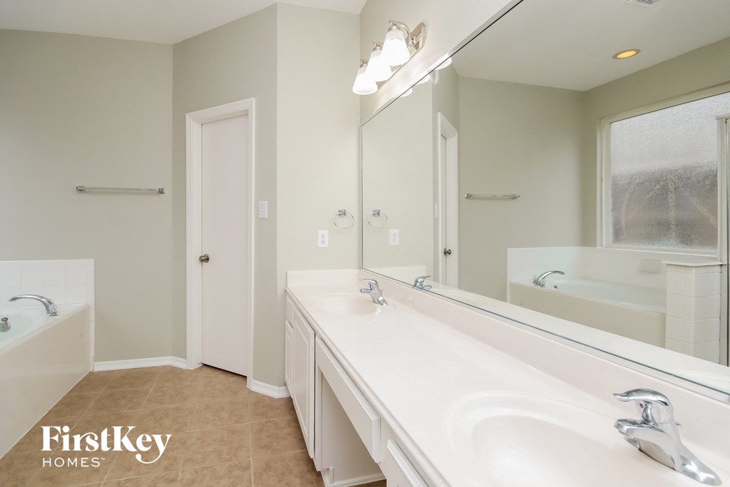 A bathroom with a large mirror and a bathtub.
