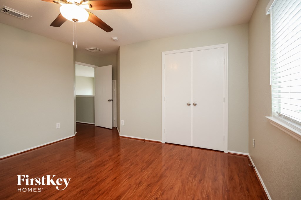 A room with a ceiling fan and wooden floors.