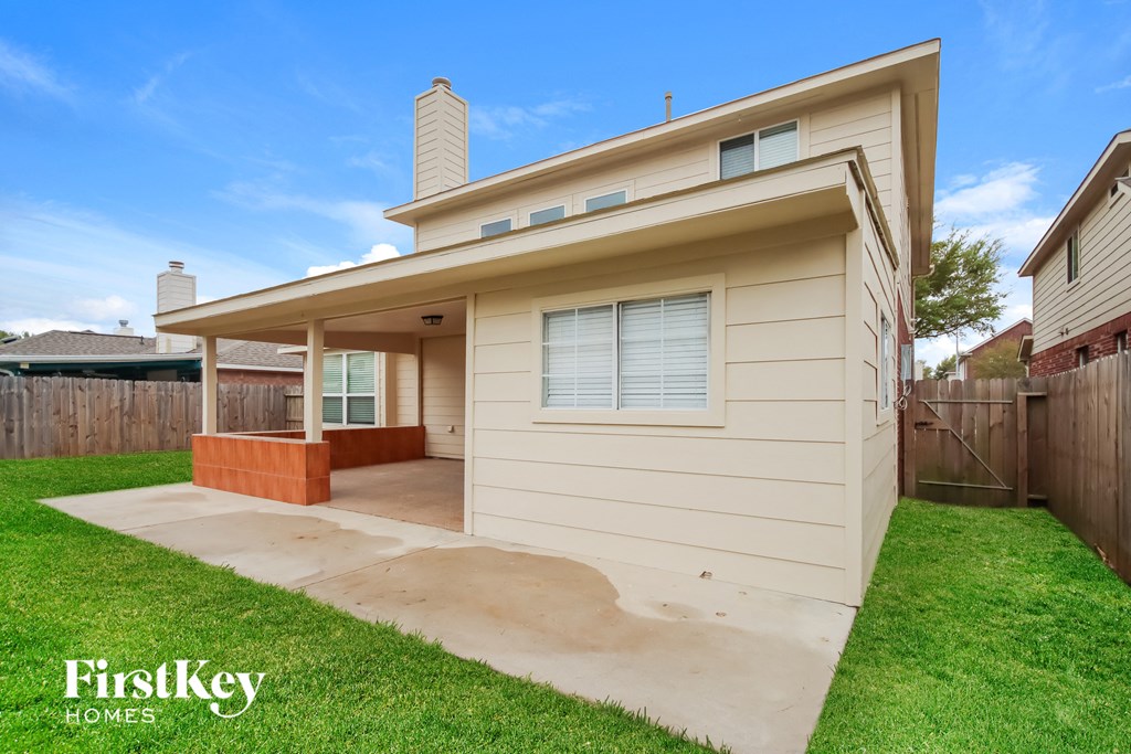 A beige house with a brown door and a brown fence.
