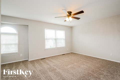 a living room with carpet and a ceiling fan
